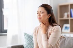 A woman suffering from a sore throat because of her air conditioning in her house not working properly