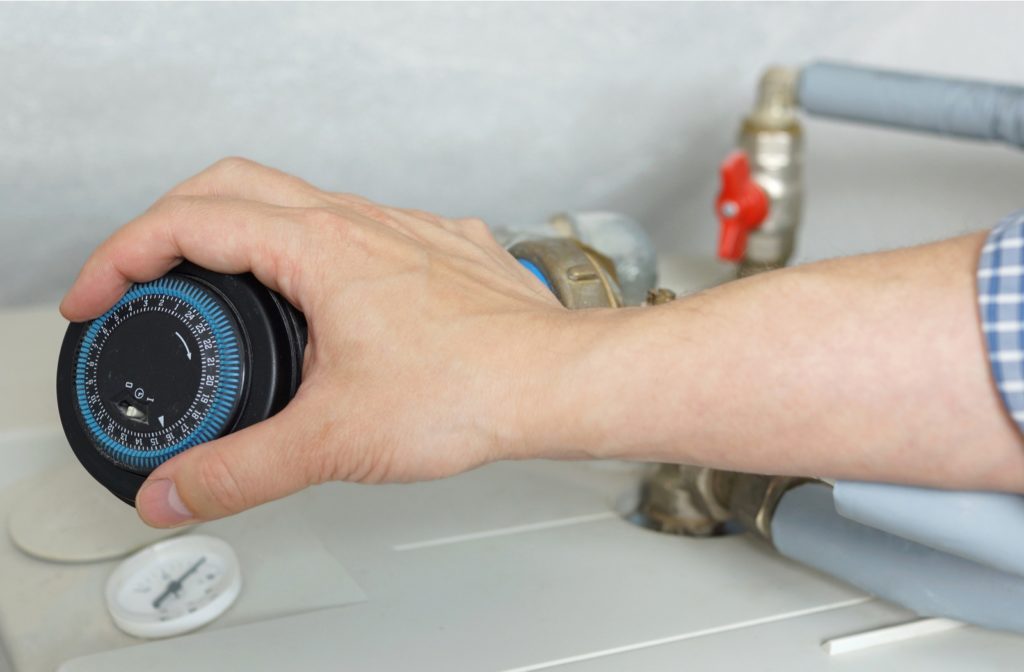 A plumber adjusting a timer on a water heater