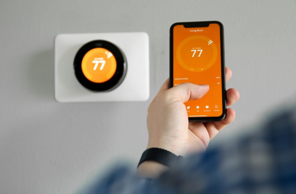 Man using smartphone app to control smart thermostat via WiFi