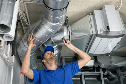A man performing a service on ductwork.