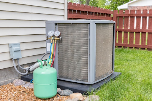 Green refrigerant canister next to outdoor AC unit.