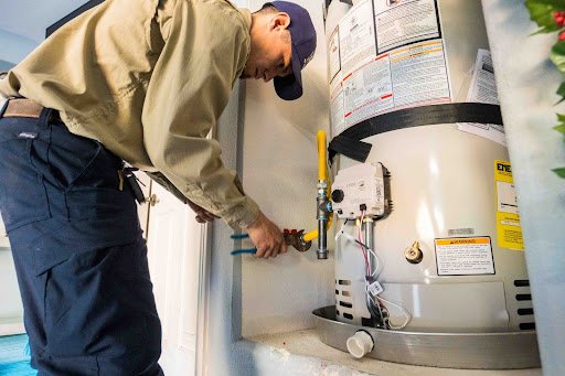 Lee's plumber adjusting water heater.