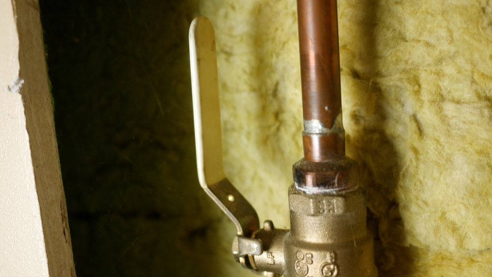 a main water shutoff valve against an exterior wall with insulation