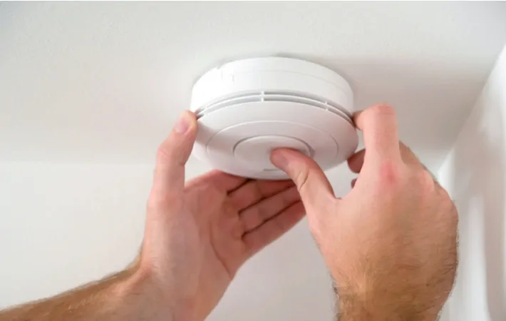 A person installing a carbon monoxide detector to protect their family from possible poisoning