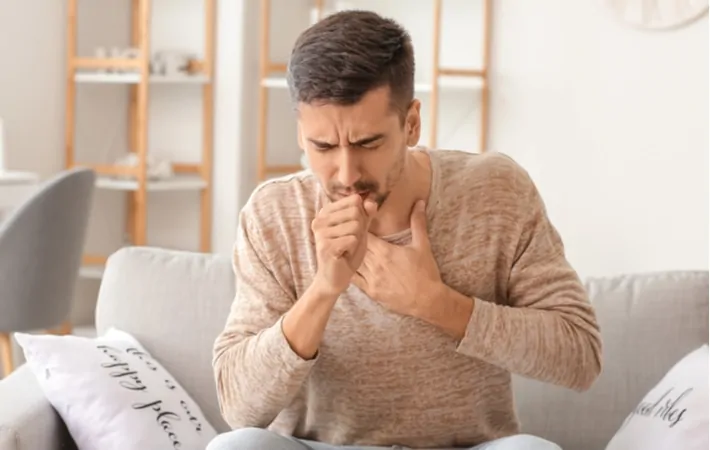 A man holding his chest coughing because of dry air