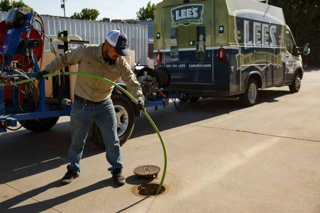 A plumber from Lee's Air, Pumbing, & Heating performing hydro jetting on a clogged drain