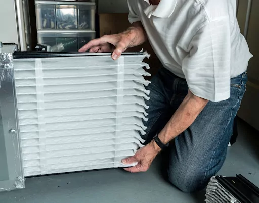 A man installing a new furnace air filter.