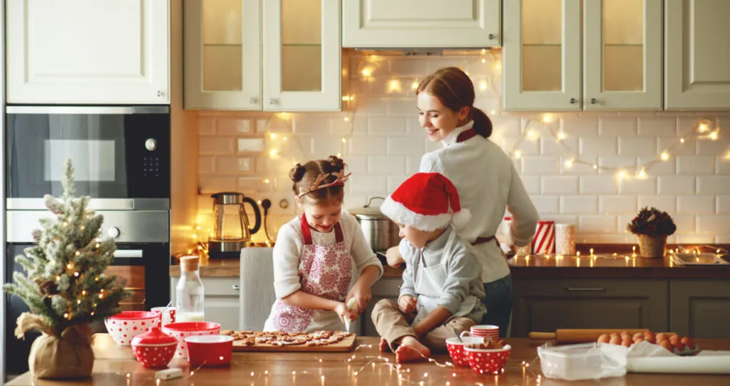 A mom and two children in the kitchen with Christmas decorations.